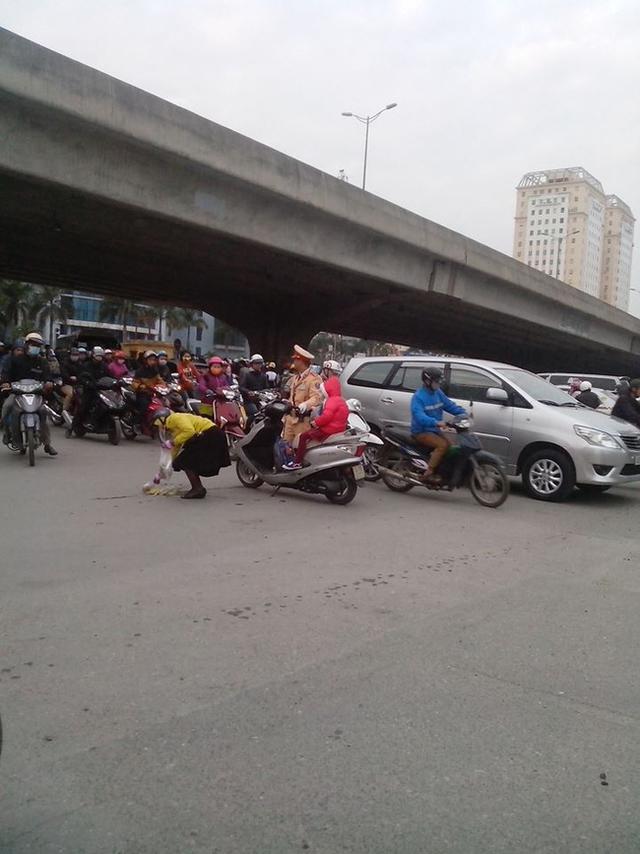 Chiến sĩ CSGT giữ xe để người mẹ nhặt cam. Ảnh: Facebook N.P.M