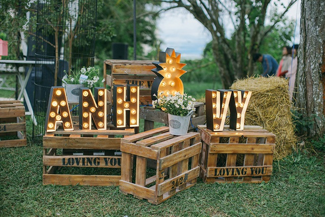 T&ecirc;n của c&ocirc; d&acirc;u v&agrave; ch&uacute; rể kỳ c&ocirc;ng với đ&egrave;n trang tr&iacute; lung linh đặt tr&ecirc;n những th&ugrave;ng gỗ mộc mạc với d&ograve;ng chữ love you.