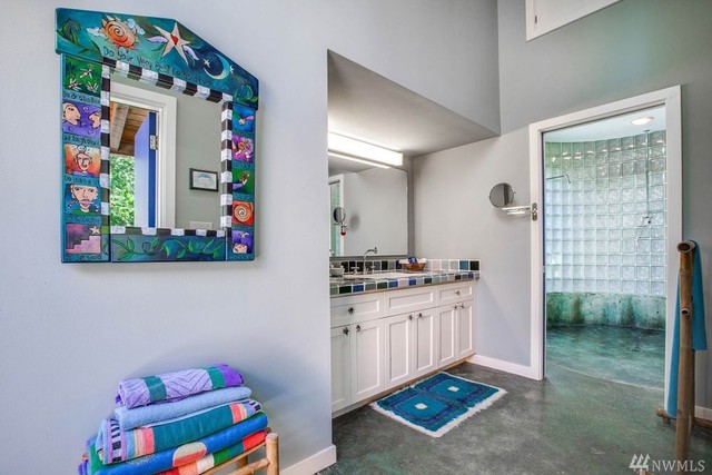 Phòng tắm gây ấn tượng khá mạnh với khung gương nghệ thuật vui nhộn, những viên gạch ốp bồn rửa màu sắc và bức tường gạch kính trong suốt bên trong phòng tắm.