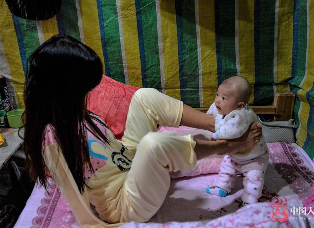 Xiang Liping (đến từ Hồ Nam, Trung Quốc) mất cả hai tay trong một tai nạn điện giật v&agrave;o năm 4 tuổi. H&igrave;nh ảnh người mẹ trẻ tự chăm s&oacute;c con d&ugrave; cơ thể kh&ocirc;ng l&agrave;nh lặn lay động h&agrave;ng triệu tr&aacute;i tim. Xiang lu&ocirc;n sống lạc quan v&agrave; c&oacute; thể l&agrave;m mọi việc như một người b&igrave;nh thường, ngoại trừ tự mặc quần &aacute;o. Ước mơ lớn nhất của c&ocirc; l&agrave; c&oacute; đ&ocirc;i tay giả để được bế v&agrave; &ocirc;m con v&agrave;o l&ograve;ng. Ảnh: QQ.