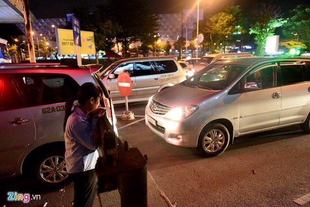 Nhân viên trạm thu phí trước cổng sân bay đứng nhìn xe vì các phương tiện không thể lăn bánh.