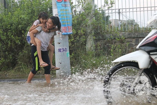 
Hai đứa bé cõng nhau đi trong dòng nước.
