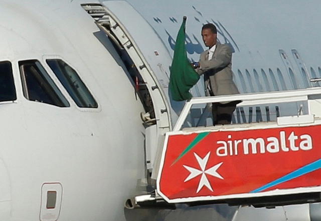 
Một trong hai t&ecirc;n kh&ocirc;ng tặc cướp chiếc m&aacute;y bay Libya bước ra cửa m&aacute;y bay, vẫy l&aacute; cờ Libya thời l&atilde;nh đạo Gaddafi. Ng&agrave;y 23/12, 2 t&ecirc;n kh&ocirc;ng tặc, tự xưng l&agrave; người ủng hộ nh&agrave; l&atilde;nh đạo bị lật đổ hồi năm 2011, đ&atilde; cướp chiếc m&aacute;y bay chở 118 người đang bay nội địa tại Libya v&agrave; &eacute;p hạ c&aacute;nh xuống Malta, đảo quốc c&aacute;ch Libya 500 km. Sau 5 tiếng cho m&aacute;y bay đậu tại s&acirc;n bay ở Malta, 2 t&ecirc;n kh&ocirc;ng tặc đ&atilde; đầu h&agrave;ng, tất cả h&agrave;nh kh&aacute;ch v&agrave; th&agrave;nh vi&ecirc;n phi h&agrave;nh đo&agrave;n an to&agrave;n. Ảnh: Reuters.
