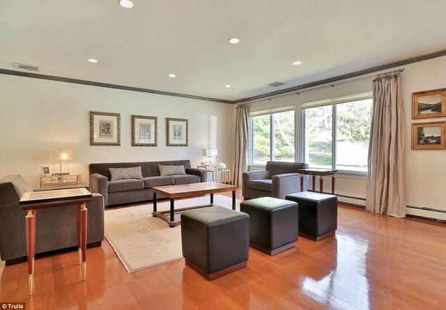 Phòng khách giản đơn với nội thất da lộn màu xám và sàn gỗ ấm áp.