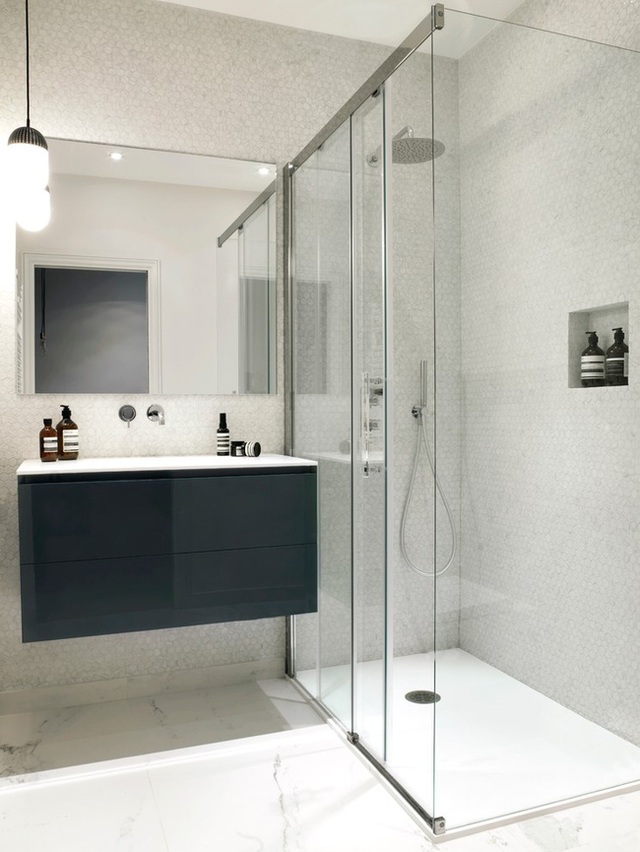 Kệ ốp tường gọn gàng và bồn tắm kính giúp đảm bảo tiện nghi cho phòng tắm nhỏ.