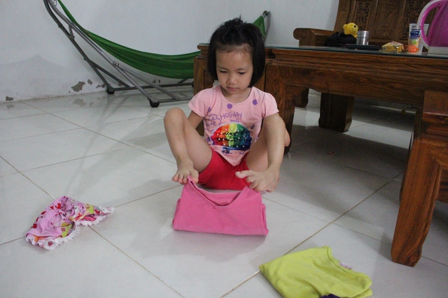 Bé Linh có thể dùng chân tự gấp quần áo cho bố mẹ và mình.