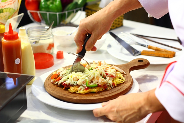 Sau khi ho&agrave;n tất b&aacute;nh pizza &ocirc;ng Hiroharu Motohashi đ&atilde; đưa đến tận b&agrave;n mời kh&aacute;ch. Tất cả c&aacute;c vị kh&aacute;ch c&oacute; mặt đều được thưởng thức m&oacute;n b&aacute;nh piza với chiếc đế s&aacute;ng tạo n&agrave;y.