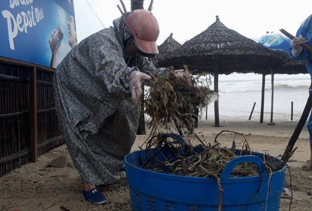 Một người dân dùng tay hốt rác, dọn sạch bãi biển.