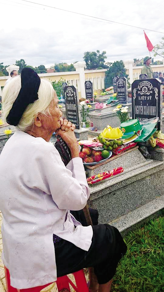 Một bà mẹ Việt Nam Anh hùng trước bia mộ của người thân đã hi sinh... Ảnh minh họa: CAND