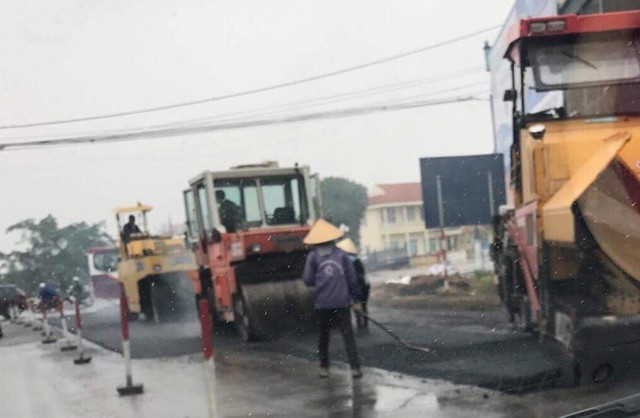 
Mặc dù trời có mưa và thời tiết lạnh, nhưng công vẫn vẫn tiến hành rải nhựa đường. Ảnh: H.Quốc
