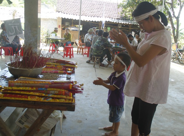 B&eacute; Kiệt cứ bắt chị Trần Thị H&agrave; (chị g&aacute;i nạn nh&acirc;n S&aacute;ng) thắp hương cho bố.
