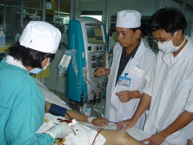 TS.BS Vũ Đình Thắng bên cạnh bệnh nhân đang được cứu sống nhờ kỹ thuật “Lọc máu hấp phụ bằng cột than hoạt tính”. Ảnh: Đỗ Bá