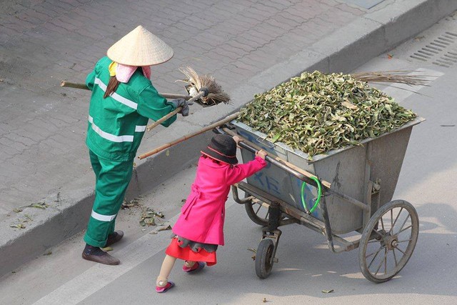 Chiều mùng 3 tết Bính Thân 2016, trên quãng đường từ Trung Văn - Mễ Trì (Hà Nội), anh Hồ Hải Hoàng chụp lại cảnh em bé mặc váy hồng cùng mẹ đẩy xe rác, cầm chổi dọn vệ sinh môi trường. Chị Trương Thị Thơm (sinh năm 1988) cho biết, 8 năm ly thân với chồng, chị gửi con cho bố mẹ chồng ở Thái Nguyên, mưu sinh ở Hà Nội. Trong lần lên Hà Nội thăm mẹ, con gái 5 tuổi nằng nặc đòi đi cùng mẹ quét rác. Không nỡ để con ở một mình, chị Thơm đành mang bé theo.