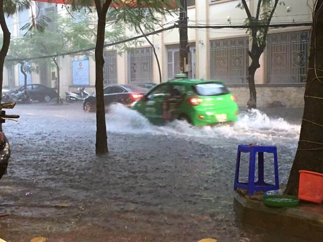 
Đường Minh Khai nước tràn lên vỉa hè khiến người đi lại khó khăn.
