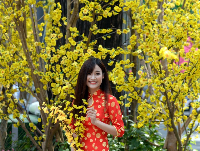 Bạn trẻ Trần Ái Nhi, 22 tuổi diện áo dài đỏ chụp hình bên cạnh những cây mai trước Nhà văn hóa Thanh Niên.