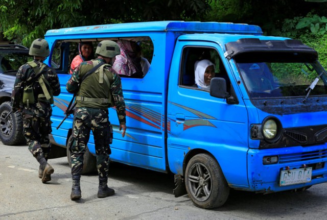 
Binh lính kiểm tra giấy tờ tùy thân của người sơ tán ở thành phố Marawi, lục soát để xem có bom hay vũ khí giấu trong xe hoặc mang theo người hay không. Ảnh: Reuters.
