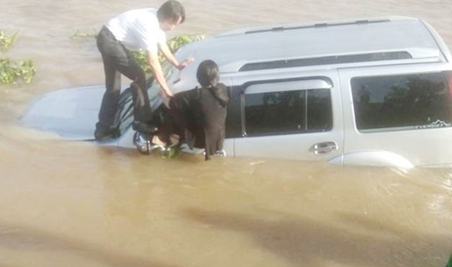 Vợ chồng &ocirc;ng &Acirc;n mở cửa &ocirc;t&ocirc; ra ngo&agrave;i sau khi xe 7 chỗ lao xuống s&ocirc;ng. Ảnh: Nguyễn Hảo.