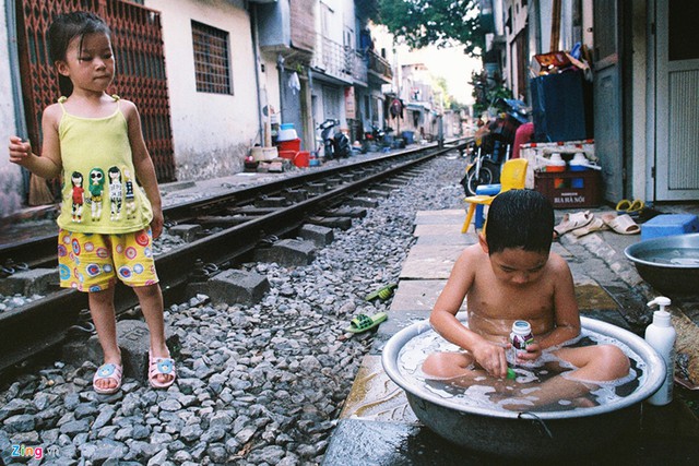 Trong bóng râm trên phố đường tầu (Phùng Hưng), một em nhỏ ngâm mình tắm mát trong chậu nước