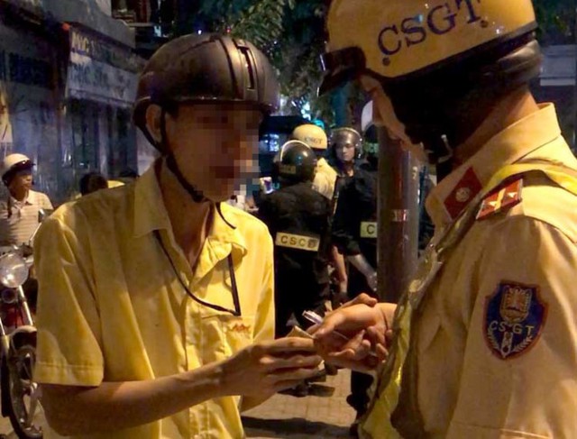 Thanh ni&ecirc;n cầm tờ giấy giống tiền đưa cho một chiến sĩ CSGT để mong bỏ qua. Ảnh: C&ocirc;ng an cung cấp.