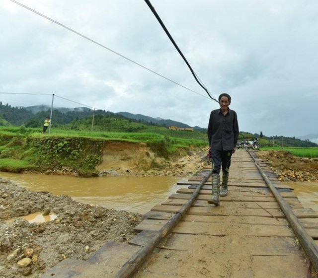 Niềm mong mỏi của ông Giàng Tống Su, 87 tuổi, đã thành hiện thực, cây cầu mới đã được khởi công - Ảnh: Nguyễn Lê
Ngày động thổ cầu Cáng Dông, bà con dân bản Páo Khắt kéo nhau rồng rắn đến xem. Họ nghe tin cây cầu sẽ được xây dựng từ cuối năm ngoái, nhưng không ngờ ngày khởi công lại nhanh đến như vậy.
Ông Giàng A Khua, trưởng bản Páo Khắt, không giấu được niềm vui: “Nghe tin được hỗ trợ, chúng tôi mừng lắm. Con suối Nậm Cai ngày bình thường trông hiền lành là thế nhưng mùa mưa bão đến lại cuồn cuộn lên ngay. Nói đâu xa, cây cầu tạm bằng gỗ dân bản cùng nhau đóng góp bắc qua suối để đi lại năm vừa rồi bị trôi mất 2 lần vì nước lớn”.
Đi qua cây cầu tạm, phụ nữ chỉ dắt bộ chứ không dám đi xe vì cầu rung lắc - Ảnh: Nguyễn Lê
 
Đúng như trưởng bản Giàng A Khua nói, cây cầu tạm bắc qua suối bằng hai thanh dầm sắt và mấy miếng gỗ sơ sài làm nền ở phía trên, mỗi khi có người đi qua đều rung lên bần bật. Chỉ có cánh đàn ông, tay lái cứng mới dám ngồi yên trên xe phóng qua cầu, còn các chị em đều phải xuống xe nổ máy, dắt từ từ qua.
Ngày 17-7 vừa rồi, cây cầu Cáng Dông làm bằng gỗ tạm lại bị nước lũ cuốn trôi trong cơn bão số 2. Đây là lần thứ 2 trong vòng chưa đầy 1 tháng, cây cầu gỗ tạm bị nước cuốn trôi khiến bà con thôn Cái Dông và Páo Khắt lại khốn khổ vì đi lại.
Theo ông Nguyễn Xuân Cường - phó tổng cục trưởng Tổng cục Đường bộ VN, cầu Cáng Dông là một trong những cây cầu được xây dựng theo chương trình “Nhip cầu yêu thương” do Chính phủ, Bộ Giao thông vận tải phát động. Chương trình kêu gọi các đơn vị, cá nhân có lòng hảo tâm cùng chung tay đóng góp, tới nay đã có 218 tổ chức, cá nhân tham gia ủng hộ với số tiền trên 470 tỉ đồng, xây dựng được 44 cây cầu dân sinh.
Con suối Nậm Cai hiền lành là thế nhưng tới mùa mưa lũ nước dâng cao, cuốn phăng cây cầu gỗ. Chỉ trong vòng chưa đầy 1 tháng (18-6 đến 17-7), cây cầu gỗ đã bị cuốn trôi 2 lần - Ảnh: Việt Hưng
Cầu Cáng Dông có tổng mức đầu tư xây dựng gần 4,4 tỉ đồng, kết cấu 2 nhịp, mỗi nhịp dài 16m, rộng 4,0m bằng bêtông cốt thép, trên móng bêtông cốt thép kiên cố.
Ông Lê Trọng Kha - phó chủ tịch UBND huyện Mù Cang Chải, chia sẻ:“Mù Cang Chải có đặc thù là huyện miền núi nên địa hình bị chia cắt rất mạnh. Hiện trên địa bàn huyện cần khoảng trên 20 cầu dân sinh bắc qua các khe suối lớn. Nhưng vì huyện nghèo nên kinh phí chưa phân bổ được để xây cầu. Được Viettel hỗ trợ như thế này, cây cầu đem đến ý nghĩa rất lớn, trước tiên là phát triển kinh tế của bà con địa phương. Người dân có thể sản xuất, vận chuyển hàng hóa ra ngoài tiêu thụ. Thứ hai là đảm bảo an toàn trong mùa mưa.
Ở miền núi mùa mưa bắt đầu từ cuối tháng 4 đến hết tháng 9, mưa lũ rất lớn, ảnh hưởng tới việc đi lại, nguy hiểm tính mạng của bà con. Có cầu kiên cố, các cháu học sinh cũng được đi học thuận tiện và đều hơn. Thứ ba, giúp địa phương hoàn thiện hơn nữa về tiêu chí nông thôn mới”.
Dân bản Páo Khắt ai cũng trông mong có cây cầu mới - Ảnh: Nguyễn Lê
 
Với Tập đoàn Viễn thông Quân đội (Viettel), Cáng Dông là cây cầu thứ 6 đơn vị này tài trợ đồng hành cùng chương trình Nhịp cầu yêu thương. Trước đó Viettel đã tài trợ và đưa vào sử dụng 5 cây cầu tại Yên Bái, Nghệ An, Quảng Trị, Lâm Đồng.
Các đơn vị đại diện động thổ khởi công công trình, mang niềm vui tới cho người dân - Ảnh: Nguyễn Lê
Trung tá Trần Quang Hưng - trưởng ban xây dựng Tập đoàn Viettel - cho hay: “Trong những năm qua, Viettel đã tổ chức nhiều chương trình, hoạt động chính sách xã hội gắn liền với vùng sâu vùng xa như chương trình Bò vì cộng đồng, Ximăng tặng hộ nghèo, Vì em hiếu học… Chương trình “Nhịp cầu yêu thương” là chương trình tiếp nối trong chuỗi hoạt động của tập đoàn. Kết nối các vùng sâu vùng xa, nâng cao đời sống của nhân dân. Góp phần củng cố quốc phòng, an ninh trên mọi miền của Tổ quốc. Tới nay, chúng tôi đã tài trợ 25 tỉ đồng xây 6 cây cầu và cam kết sẽ có nhiều hoạt động hỗ trợ vào các năm tiếp theo”.
Sau hơn 2 năm, Chính phủ, Bộ Giao thông vận tải phát động chương trình “Nhịp cầu yêu thương” nhằm kêu gọi mọi người có lòng hảo tâm cùng chung tay đóng góp, đã có 44 cầu dân sinh được thực hiện, 36 công trình được đưa vào khai thác sử dụng. Tới năm 2020 chương trình dự kiến sẽ xây dựng thêm 2.300 cây cầu trên 50 tỉnh thành trong cả nước, chủ yếu là vùng đồng bào dân tộc miền núi.
Theo Thu Thảo/Tuổi trẻ