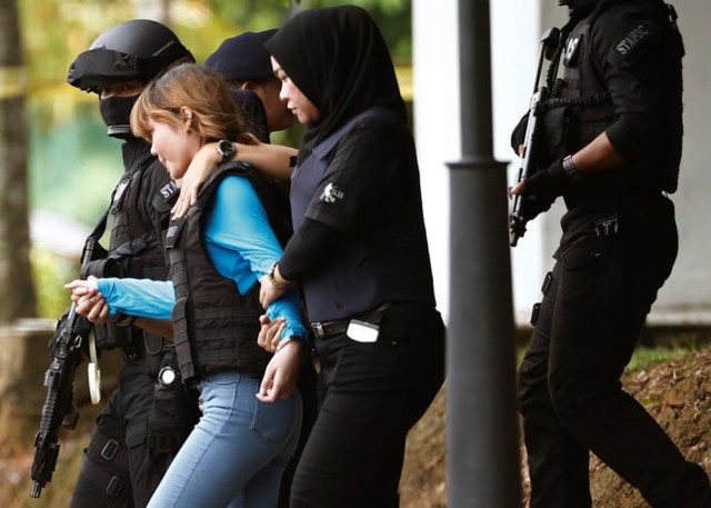 
Đoàn Thị Hương (áo xanh) mặc áo chống đạn và được áp tải khỏi tòa hôm 13/4. Ảnh: Reuters.
