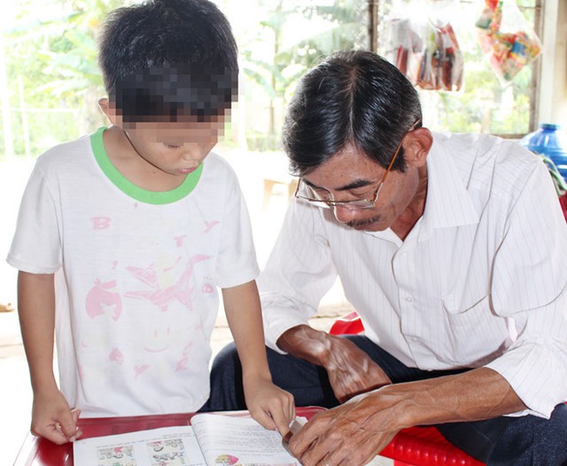 
Hiệu trưởng Huỳnh Hà Thắng trực tiếp kiểm tra việc đọc chữ của em L. Ảnh: CTV.
