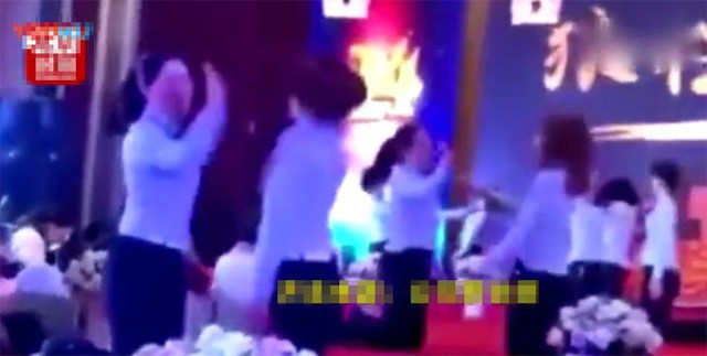 C&aacute;c nữ nh&acirc;n vi&ecirc;n mặc đồng phục v&agrave; bị bắt quỳ tr&ecirc;n s&acirc;n khấu.