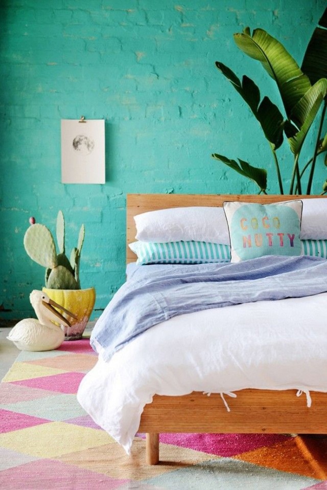 Một phòng ngủ với bức tường gạch được sơn màu ngọc lam nhẹ nhàng - tương phản với tấm thảm hình học màu đậm khiến cho phòng ngủ có cảm giác tươi mới.