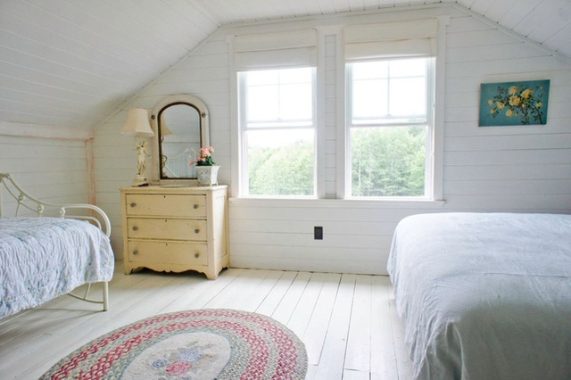 Phòng ngủ có 2 cửa sổ, đem đến không gian tràn đầy ánh sáng. Màu trắng của ga gối tương đồng với sắc màu trên tường. Chiếc tủ màu vàng nhạt trở thành điểm nhấn hoàn hảo.