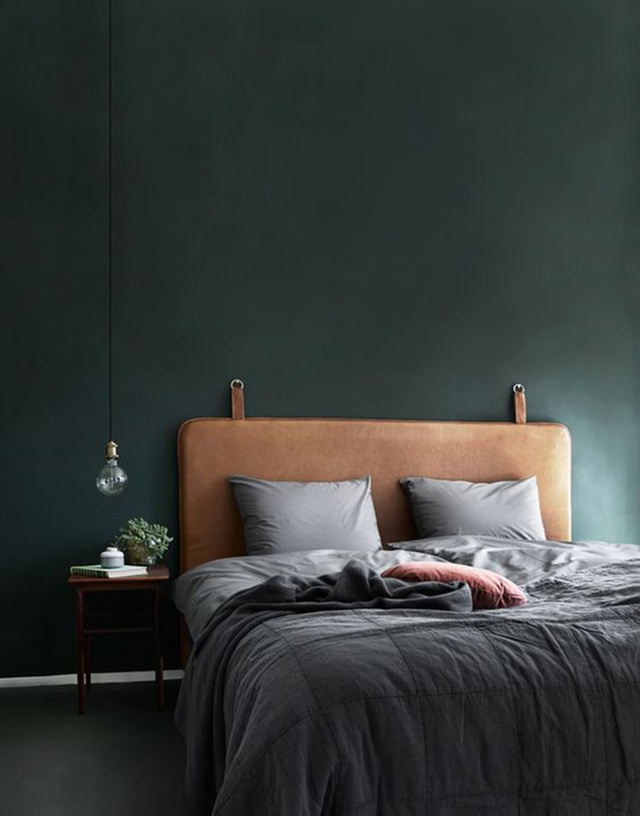 Một chiếc giường nệm da màu nâu với một bức tường màu xanh lá cây đậm tạo nên vẻ nam tính cho phòng ngủ.