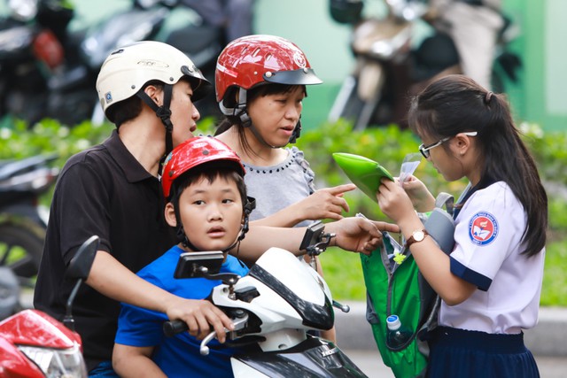 Cả gia đình đồng hành cùng thí sinh đến điểm thi, chị Hòa động viên con gái trước giờ thi. lưu ý con xem lại giấy tờ, bút viết.