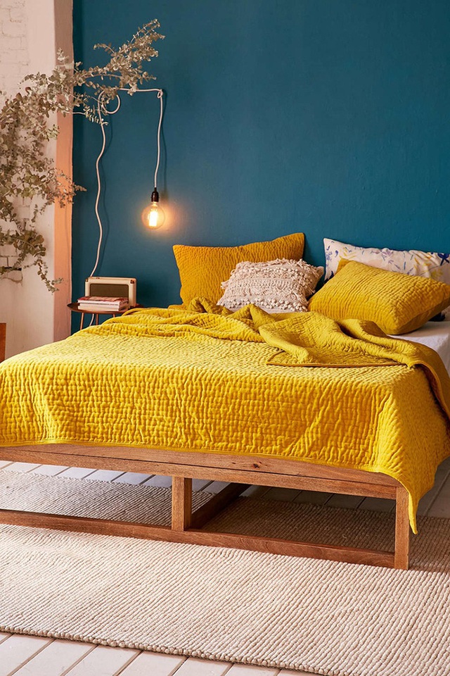 Bức tường màu xanh navy tương phản với bộ ga gối giường màu vàng của nắng.