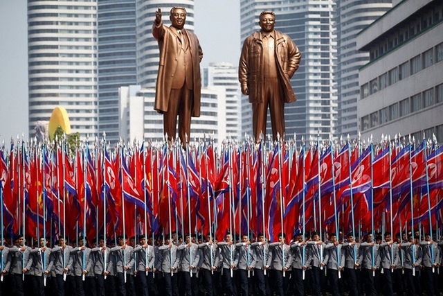 
Người cầm cờ trước tượng Kim Nhật Thành và cố lãnh đạo Kim Jong-il. Ảnh: Reuters

