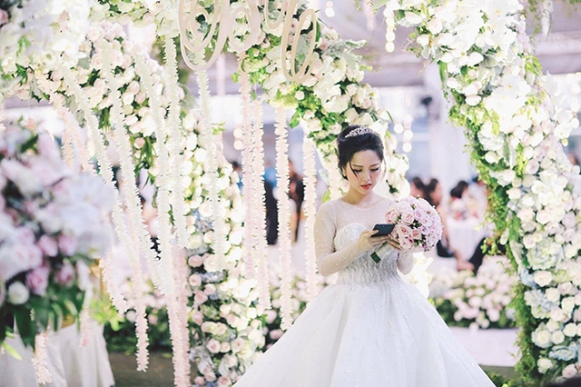 
Wedding planner sử dụng 15.000 bông hoa hồng, 3.000 bông hoa cẩm tú cầu kích thước lớn, 3.000 chiếc lá tai dừa, 100 cành lan hồ điệp cùng hàng trăm bó lá cho khu vực sân khấu, sảnh đón khách và bàn tiệc.
