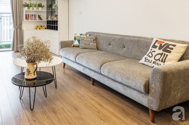 Ghế sofa với những đường nét mềm mại kết hợp hài hòa với bàn trà, nơi được trang trí với chậu hoa dịu dàng cho cuộc sống trên cao của gia đình trẻ thêm bình yên.