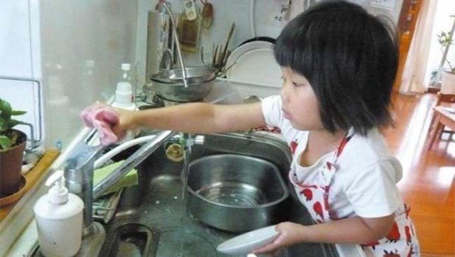Cô bé cũng học cách rửa chén bát. (Ảnh: NTD)