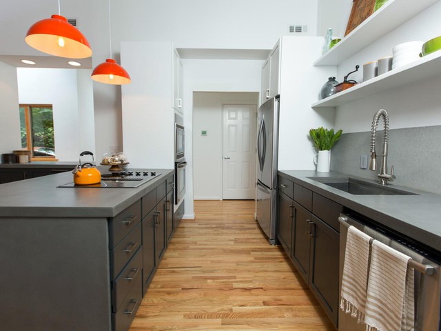 Hệ thống tủ bếp phía trên được thay bằng kệ mở màu trắng tạo cảm giác thông thoáng cho phòng bếp. Hai chiếc tủ cao đứng đối diện nhau bên trong cũng được thay bằng gam màu trắng sạch sẽ. Còn lại, toàn bộ hệ thống tủ bếp bên dưới ở hai bên bếp đều là màu ghi đen sạch sẽ.