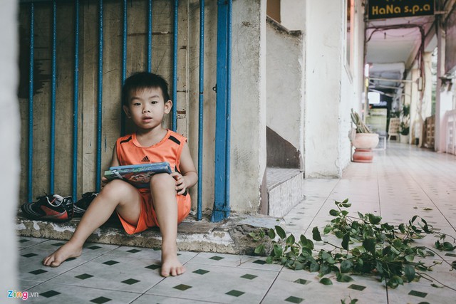 Bé Tuấn Khang (4 tuổi), đang ngồi chơi máy tính bảng ở trước nhà trong lúc bố bé đang tỉa cây cảnh.