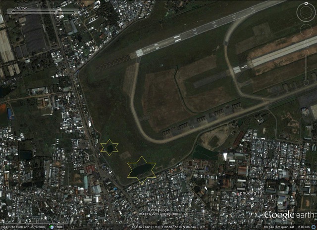 Không ảnh vệ tinh của Google Earth chụp ngày 27/09/2000, vị trí được cho là hai hố chôn tập thể (Hình nhỏ là vị trí hố chôn đã cải táng năm 1995, hình lớn là vị trí hố chôn chưa xác định)