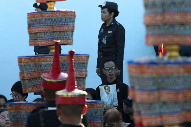Một người đ&agrave;n &ocirc;ng cầm di ảnh của cố vương Adulyadej trong buổi tập dượt. Ảnh: REUTERS