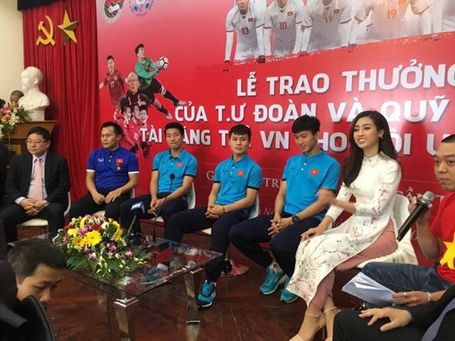 Mỹ Linh diện áo dài màu trắng hoa nhí đẹp nền nã bên các tuyển thủ trẻ của đội U23 Việt Nam.