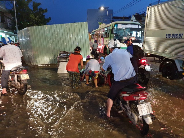 Người dân Sài Gòn giúp nhau trong những ngày triều cường dâng cao (trong ảnh một c&ocirc; g&aacute;i bị ng&atilde; xe khiến đồ đạc bị ướt hết)
