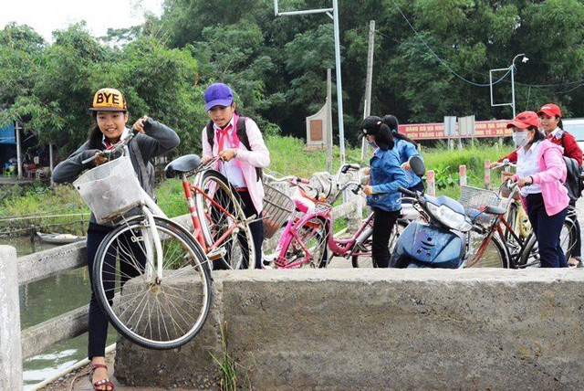 Nhiều chục học sinh trường THCS Duy Vinh leo qua lớp bê tông để đi qua cầu Các em học sinh giúp nhau di chuyển xe đạp qua dải bê tông
