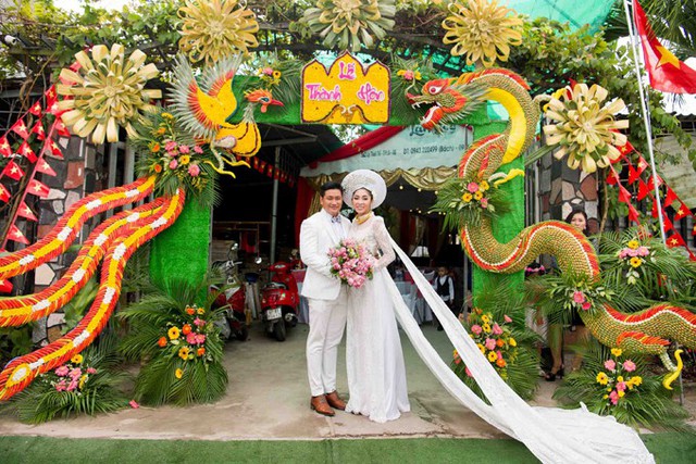 Cổng hoa nhà chồng Đặng Thu Thảo trang trí ấn tượng với hình long, phụng kết từ lá dừa và các loại trái cây đặc trưng ở miền Tây Nam Bộ.
