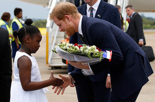 Harry bắt tay cô bé Jane Chawanangwa, đại diện trẻ em Zambia, ra tặng hoa và chào đón hoàng tử nước Anh ở sân bay Lusaka chiều 26/11. Ảnh: Reuters.