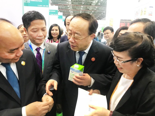 Thủ tướng Chính phủ Nguyễn Xuân Phúc và Thứ trưởng Bộ Thương mại Trung Quốc Vương Bính Nam tìm hiểu về sản phẩm sữa tươi hữu cơ TH true MILK organic tại gian hàng trưng bày của tập đoàn TH.