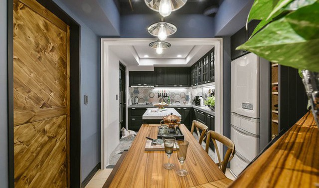 
Chất liệu gỗ được sử dụng cho bàn ăn, chất liệu gạch được sử dụng làm điểm nhấn cho gian bếp như sàn gần bếp nấu và bức tường cạnh bếp. Hệ thống tủ đựng đồ vẫn được chọn màu xanh xám để tạo sự kết nối hài hòa với khu vực tiếp khách.

