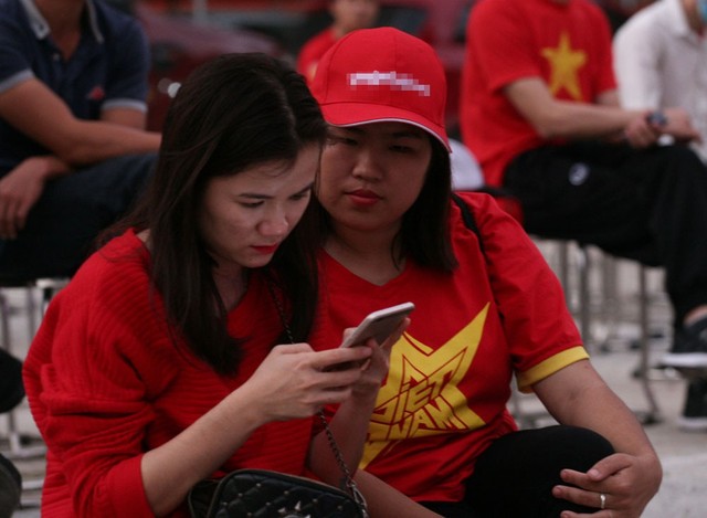 Một số nữ cổ động viên đọc thông tin trên mạng xã hội trước giờ bóng lăn.
