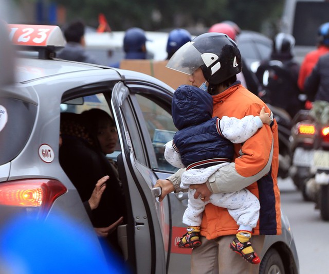 Một người đàn ông ôm con mình để về quê bằng taxi sau thời gian dài chờ xe khách không được.