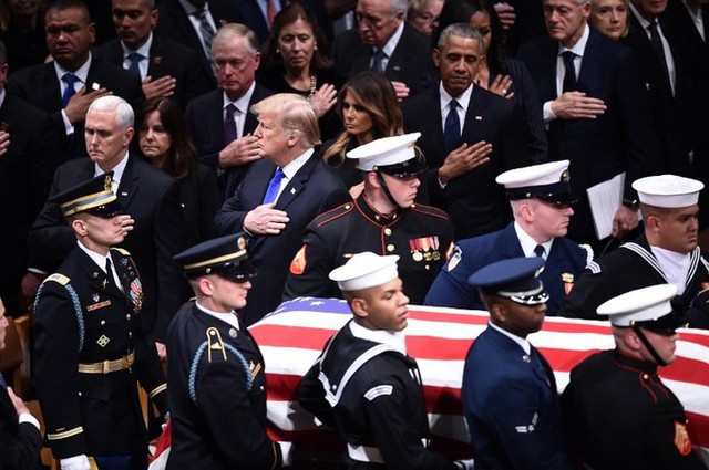 Các cặp vợ chồng tổng thống đứng lên, đặt tay lên ngực trái để thể hiện sự tôn kính khi linh cữu cố tổng thống Bush được đưa vào nhà thờ. Ảnh: AFP.